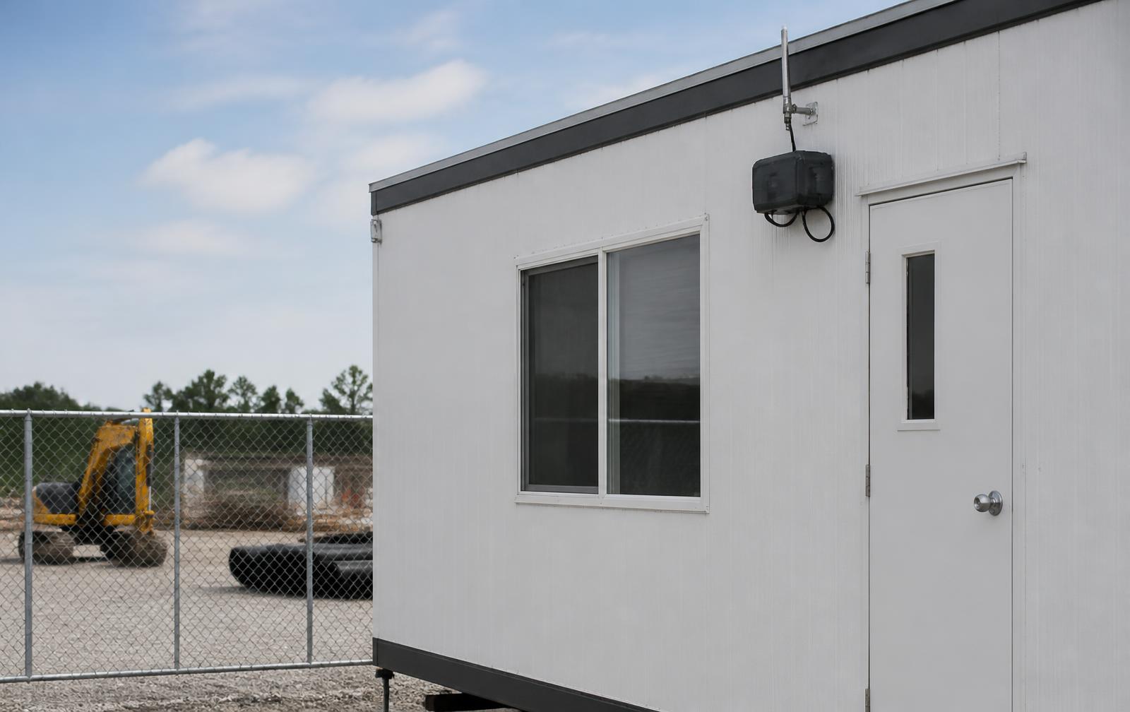 A site office trailer with an Oasis unit and antenna mounted on its exterior wall